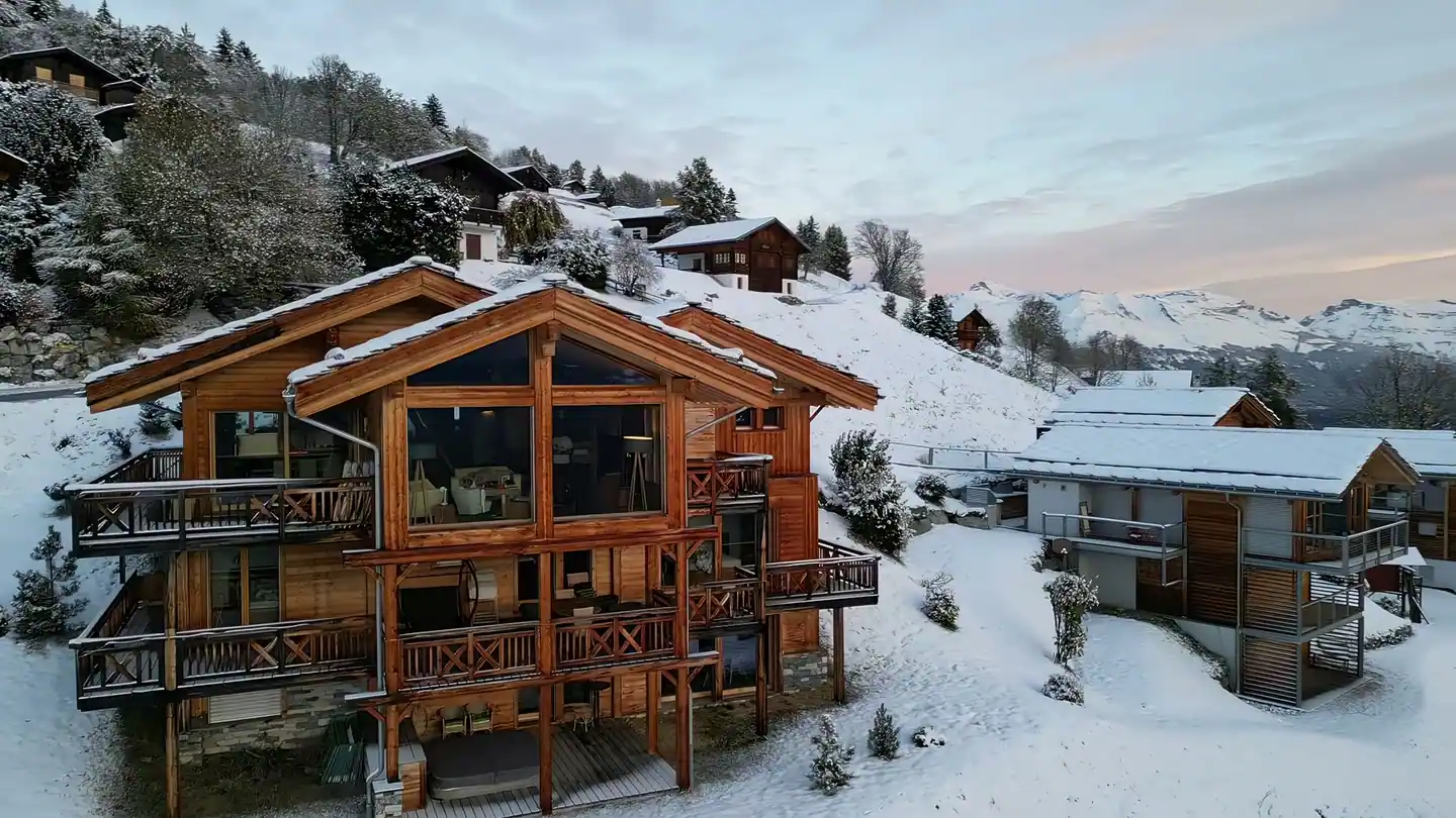 The chalet front in winter: glass gable and wooden balconies