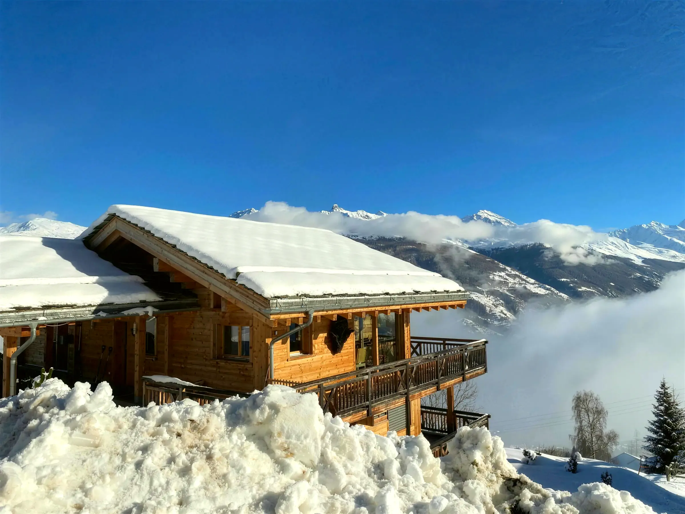 Chalet zimą nad morzem chmur, w tle ośnieżone szczyty