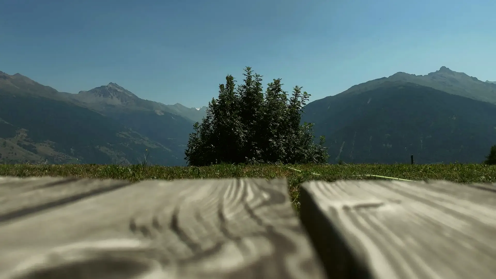 Wooden table on the chalet terrace in summer, with mountains behind